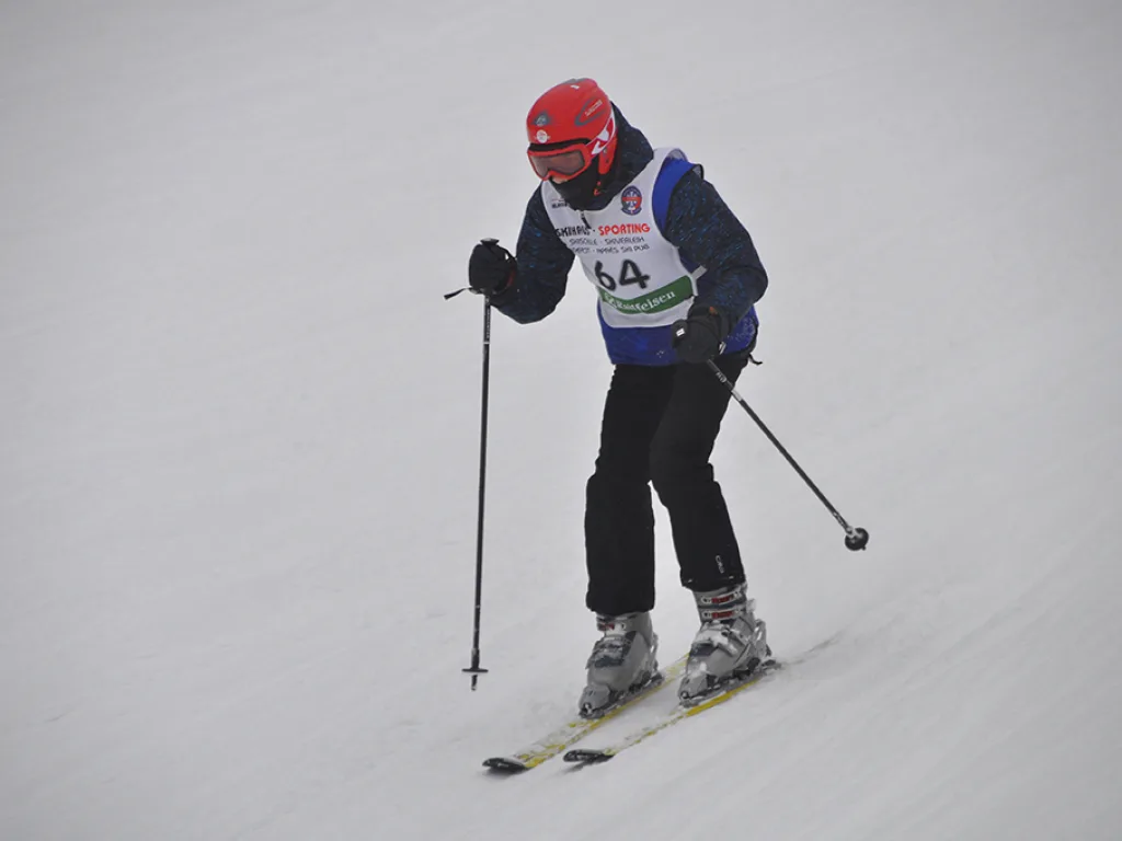 Skifahrer mit Startnummer 64 und roter Mütze.